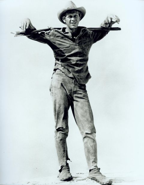 Max (McQueen) with gun slung over both shoulders.